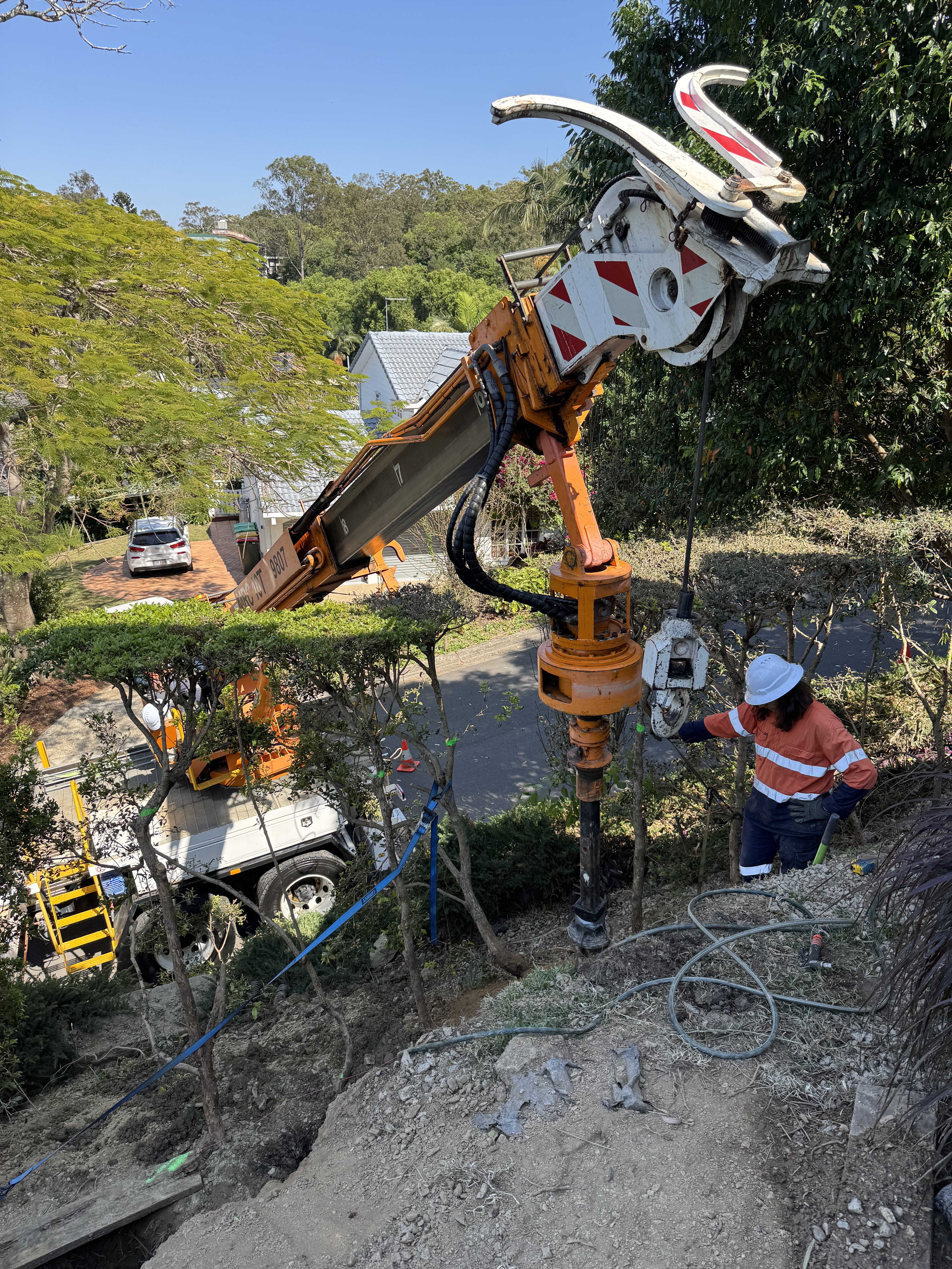 Bored pier installation for retaining wall engineering on steep site